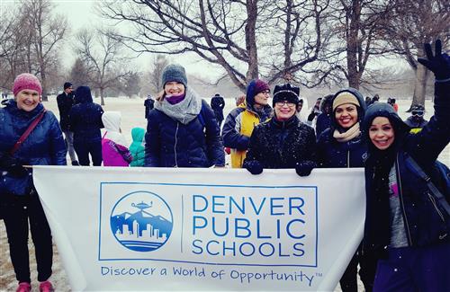 Women in snow holding a DPS Banner 